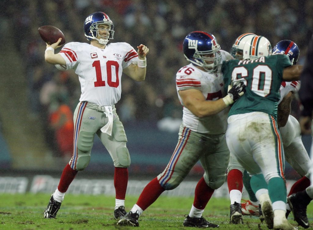 New York Giants' Eli Manning quarter back (10) throws the ball whilst Miami Dolphins, Stiveni Fifita (60 ) is held back during the second quarter of their NFL football game at Wembley Stadium in London, Sunday, Oct. 28, 2007. (AP Photo/Kirsty Wigglesworth)